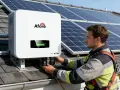 Instalator podłącza falownik 40kW do paneli słonecznych na dachu.