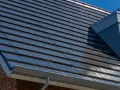 Nowoczesny dach z ciemną dachówką fotowoltaiczną, która dyskretnie integruje się z architekturą domu, zapewniając czystą energię.
