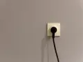 Gniazdko elektryczne z wtyczką na szarej ścianie. Czy to symbol energa taryfa urzędowa?