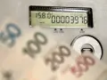 Opłata kogeneracyjna co to? Licznik energii i banknoty 50, 100, 200, 500 zł sugerują wysokie rachunki za prąd.