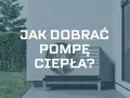 Jak obliczyć moc pompy ciepła? Na zdjęciu jednostka zewnętrzna pompy ciepła przy ścianie domu, otoczona zielenią.