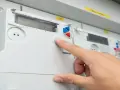 Dłoń naciska przycisk na liczniku energii elektrycznej, na wyświetlaczu widoczna jest taryfa G12n.