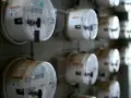 Rząd liczników energii elektrycznej, każdy z plombą. Jeden z nich, jako sprzedawca rezerwowy, jest widoczny z bliska.