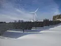 Panele fotowoltaiczne i wiatrak na tle zimowego krajobrazu. Rozliczenie z PGE za energię odnawialną.