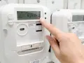 Palec naciska przycisk licznika energii elektrycznej, sprawdzając opłatę mocową.