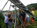 Uczestnicy kursu fotowoltaika montują panele słoneczne. Grupa mężczyzn przygląda się konstrukcji.