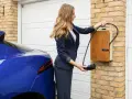 Kobieta podłącza niebieski samochód elektryczny do ładowarki. Szybkie ładowanie dzięki sile 400V.