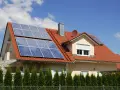 Dom z czerwoną dachówką i panelami fotowoltaicznymi. Mikroinstalacja PV na dachu zapewnia czystą energię.