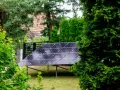 Panele fotowoltaiczne w ogrodzie, otoczone zielenią, czerpią energię ze słońca.