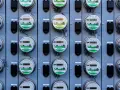 Rząd liczników energii elektrycznej, zgodnych z dyrektywą MID, z cyfrowymi wyświetlaczami i zielonymi etykietami.