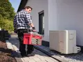 Technik z walizką narzędziową przy pompie ciepła. Może sprawdzać kody błędów urządzenia.