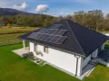Nowoczesny dom jednorodzinny z panelami słonecznymi na dachu. Obniżone miesięczne zużycie prądu dzięki odnawialnym źródłom energii.