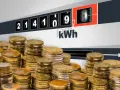 Liczniki energii pokazują zużycie kWh, a stosy monet sugerują pytanie: ile za kWh Tauron?