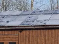 Panele fotowoltaiczne na drewnianym budynku. Widać ich kolejność włączania instalacji fotowoltaicznej.