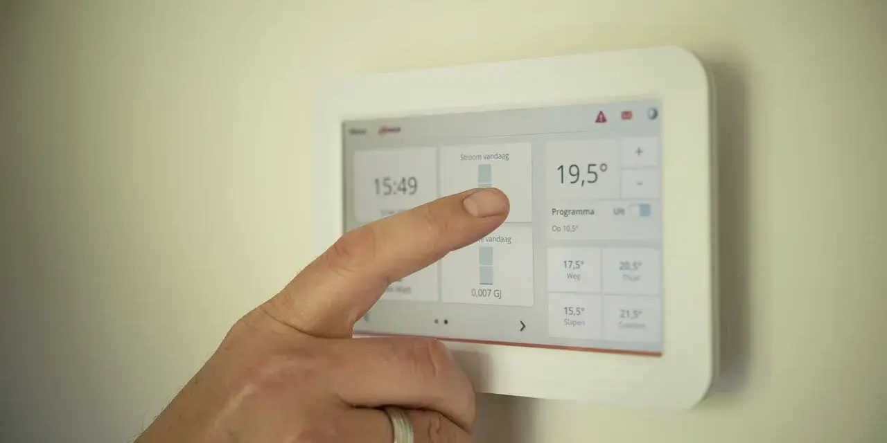 Dłoń dotyka ekranu, pokazując jak ustawić temperaturę w pompie ciepła. Widoczna aktualna temperatura 19,5°C.