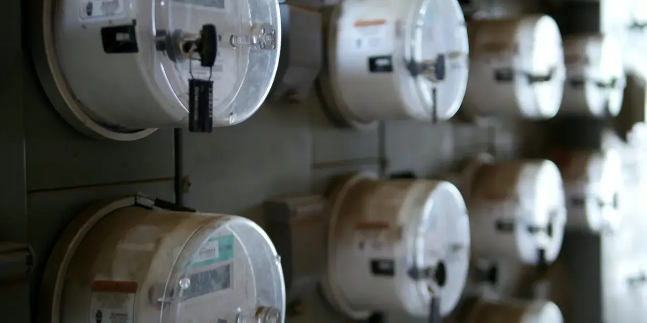 Rząd liczników energii elektrycznej, każdy z plombą. Jeden z nich, jako sprzedawca rezerwowy, jest widoczny z bliska.