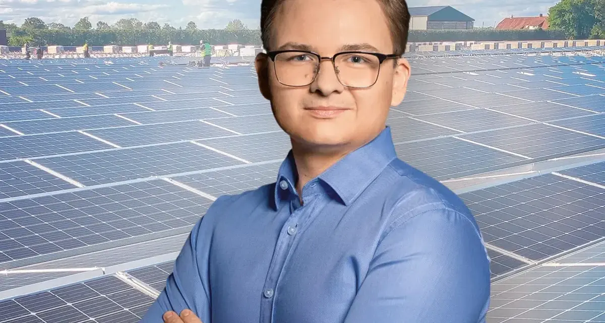 Mężczyzna w okularach na tle farmy fotowoltaicznej. Szanuj energię, nie daj się oszustom.