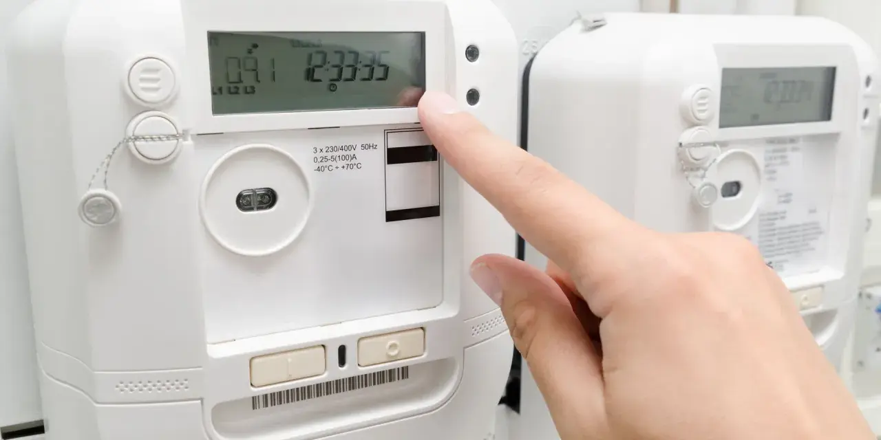 Palec naciska przycisk licznika energii elektrycznej, sprawdzając opłatę mocową.