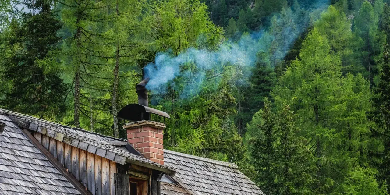 Dym z komina chatki w lesie. Czy to znak, że jeszcze można palić starym piecem na wsi, czy już czas na wymianę?