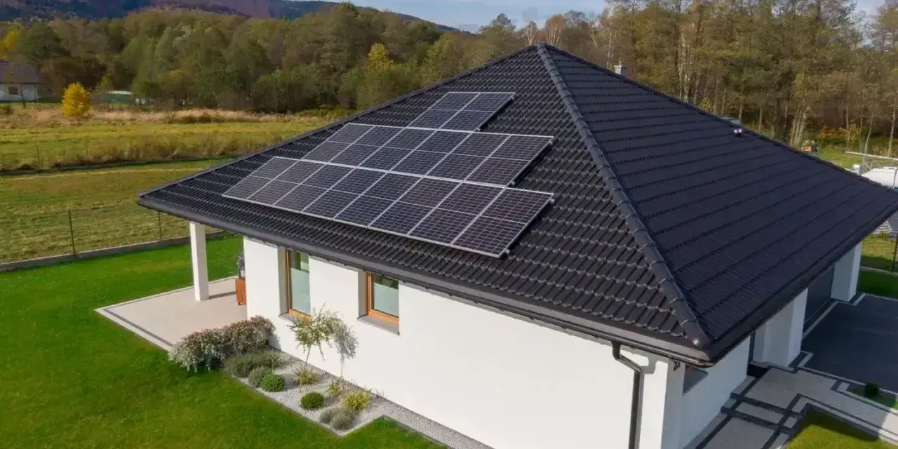 Nowoczesny dom jednorodzinny z panelami słonecznymi na dachu. Obniżone miesięczne zużycie prądu dzięki odnawialnym źródłom energii.