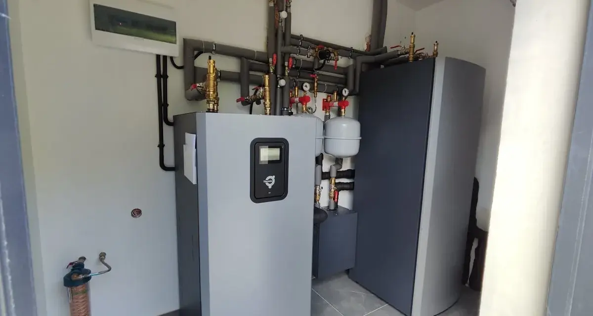 Nowoczesna instalacja grzewcza z pompą ciepła wysokotemperaturową, zbiornikiem i systemem rur.