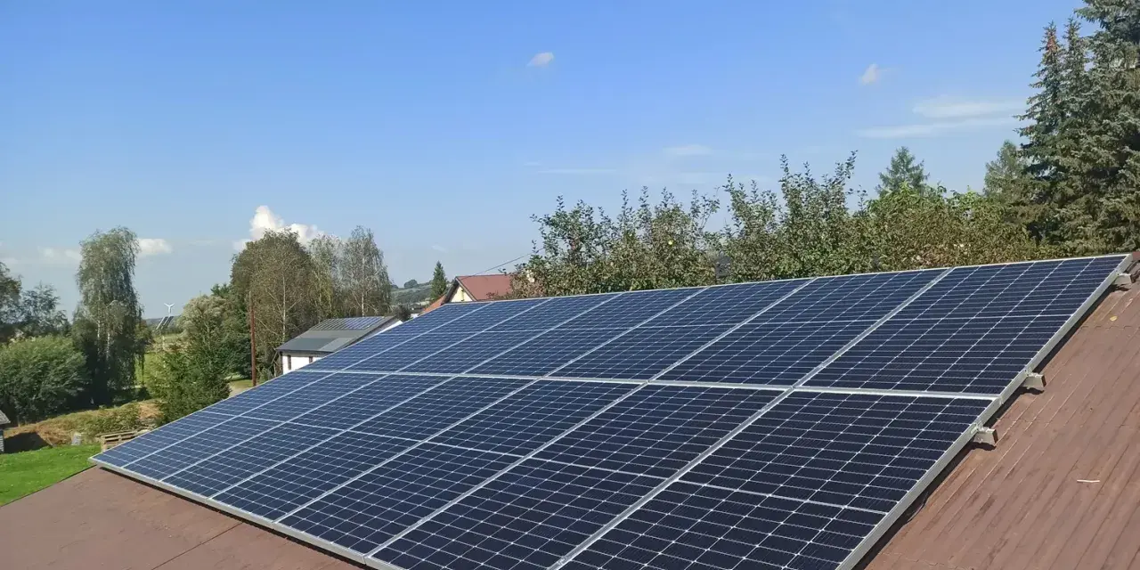 Panele fotowoltaiczne na dachu. Zastanawiasz się nad rozliczeniem rocznym czy miesięcznym? Słońce świeci, produkując czystą energię.