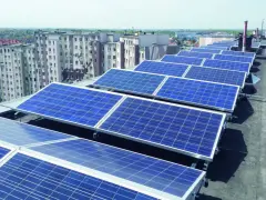 Panele fotowoltaiczne na dachu bloku mieszkalnego, zapewniające zieloną energię dla mieszkańców.