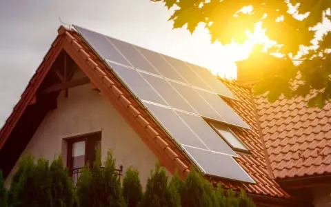 Panele słoneczne na dachu domu. To przykład, jak działa prosument, produkując własną energię.