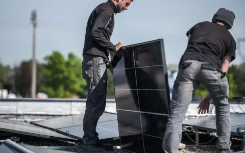 Pracownicy montują panele fotowoltaiczne, przygotowując zgłoszenie rozbudowy instalacji fotowoltaicznej PGE.