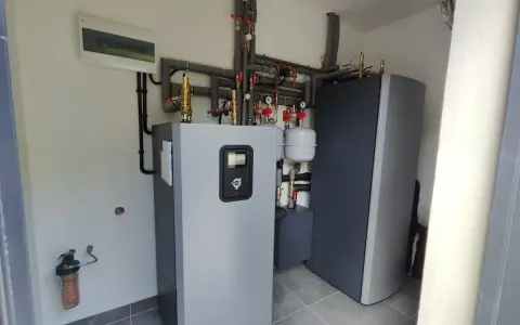 Nowoczesna instalacja grzewcza z pompą ciepła wysokotemperaturową, zbiornikiem i systemem rur.