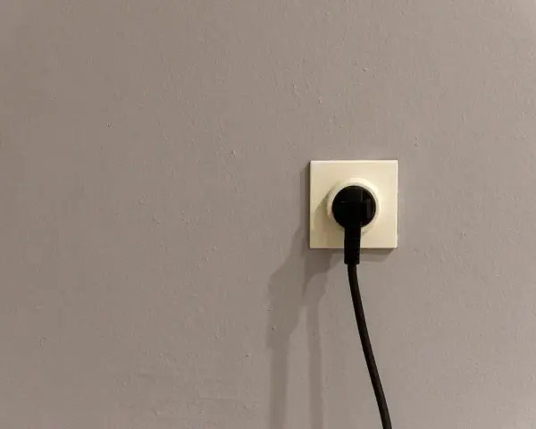 Gniazdko elektryczne z wtyczką na szarej ścianie. Czy to symbol energa taryfa urzędowa?