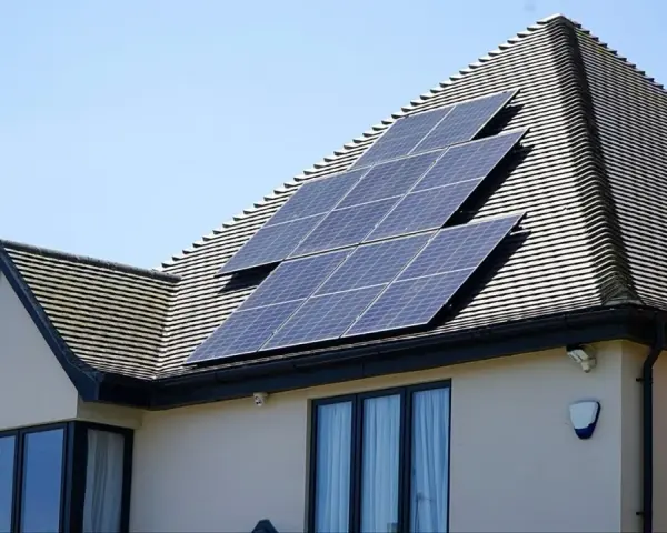 Panele fotowoltaiczne na dachu domu, działające jako agregator energii, łapią promienie słoneczne.