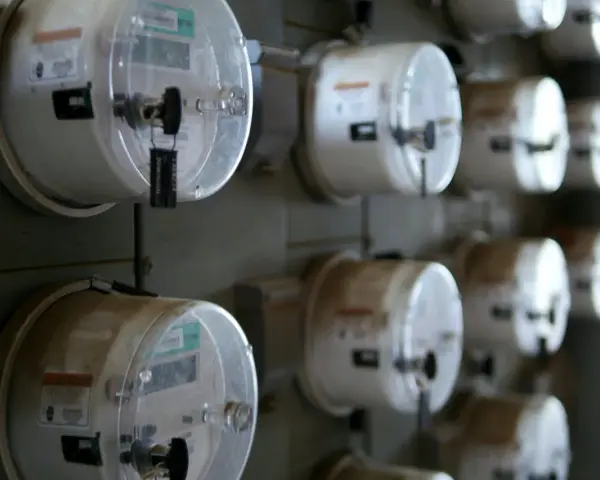 Rząd liczników energii elektrycznej, każdy z plombą. Jeden z nich, jako sprzedawca rezerwowy, jest widoczny z bliska.