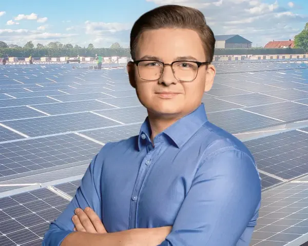 Mężczyzna w okularach na tle farmy fotowoltaicznej. Szanuj energię, nie daj się oszustom.