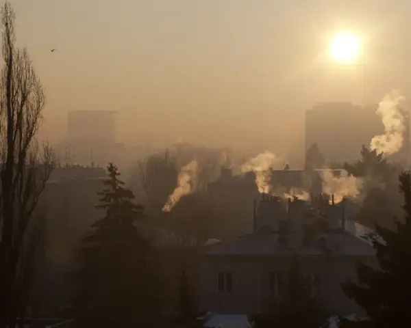Mglisty poranek, słońce przebija się przez dym z kominów. Czas pomyśleć, do kiedy trzeba wymienić piec, by powietrze było czystsze.