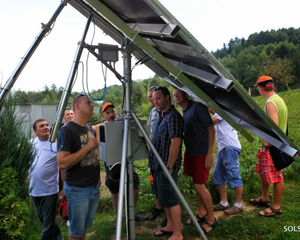 Uczestnicy kursu fotowoltaika montują panele słoneczne. Grupa mężczyzn przygląda się konstrukcji.