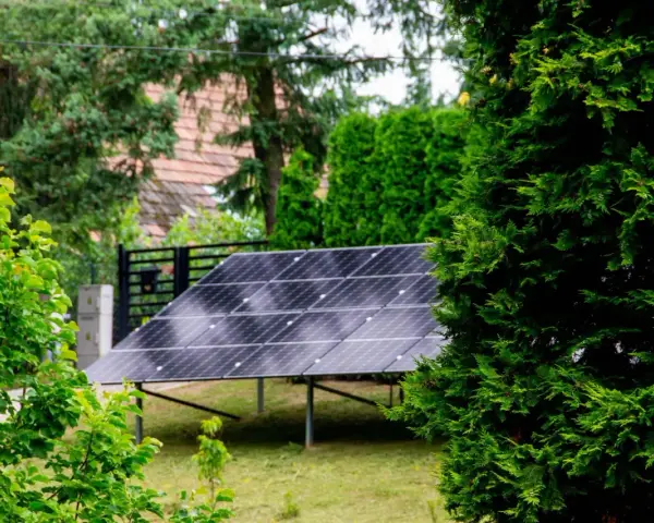 Panele fotowoltaiczne w ogrodzie, otoczone zielenią, czerpią energię ze słońca.