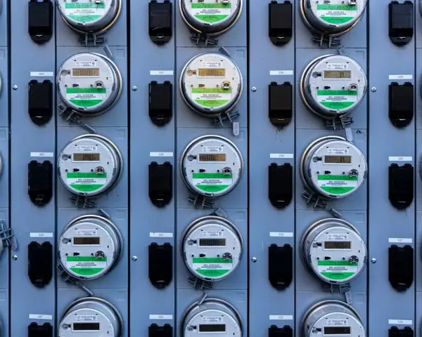 Rząd liczników energii elektrycznej, zgodnych z dyrektywą MID, z cyfrowymi wyświetlaczami i zielonymi etykietami.