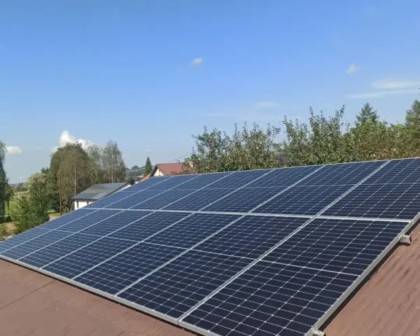Panele fotowoltaiczne na dachu. Zastanawiasz się nad rozliczeniem rocznym czy miesięcznym? Słońce świeci, produkując czystą energię.