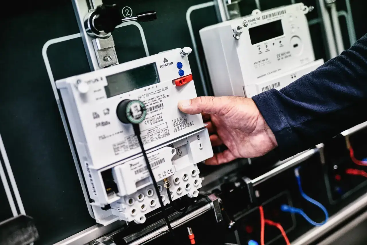 Ręka montuje licznik energii elektrycznej, przygotowując pge ponowne podłączenie prądu.