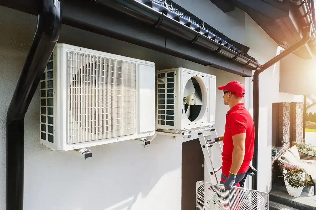 Instalator montuje jednostkę zewnętrzną pompy ciepła. Dobra pompa ciepła do domu 100m2 to klucz do oszczędności.