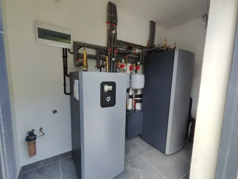 Nowoczesna instalacja grzewcza z pompą ciepła wysokotemperaturową, zbiornikiem i systemem rur.